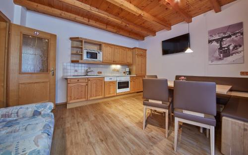 a kitchen with wooden cabinets and a table with chairs at Appartements 4-You in Saalbach-Hinterglemm