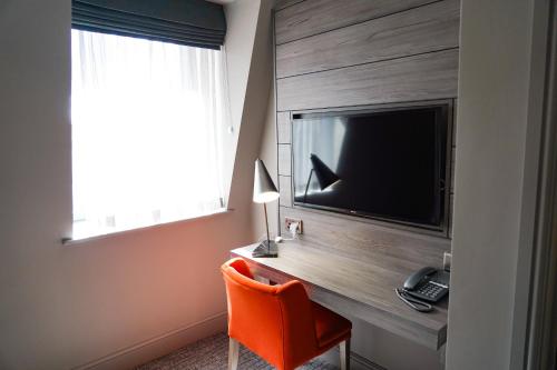 a room with a desk with a television and a chair at Great North Hotel in Newcastle upon Tyne