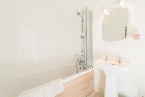 y baño blanco con lavabo y bañera. en My Place Go - Cirencester, en Cirencester