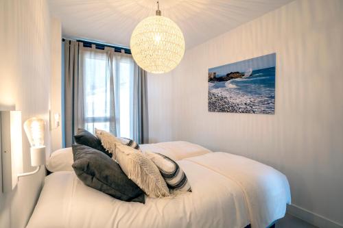 a bedroom with a white bed and a chandelier at Sealine luxury apartment in Torrox Costa in Torrox Costa