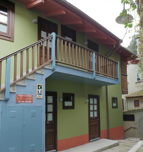 a house with a balcony and a blue garage at Villa Cudillero - recep H Isabel in Cudillero