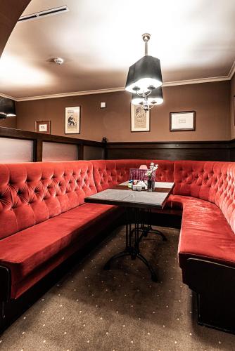 a red couch in a bar with a table at La Contessa Castle Hotel in Szilvásvárad