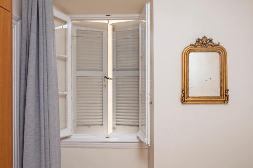 een raam met witte luiken en een spiegel bij Downtown Apt at Filellinon in Corfu-stad