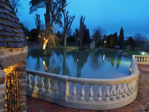 - une piscine dans un jardin la nuit avec une clôture blanche dans l'établissement Logis Hotel Oasis, à Villaines-la-Juhel