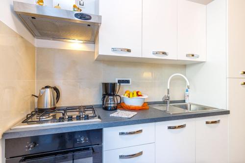 a kitchen with white cabinets and a stove and a sink at Maximilian&Stela in Poreč