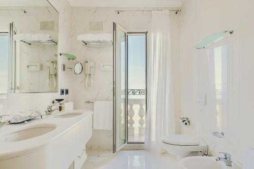 a white bathroom with two sinks and a toilet at Casa Bianca Al Mare in Lido di Jesolo