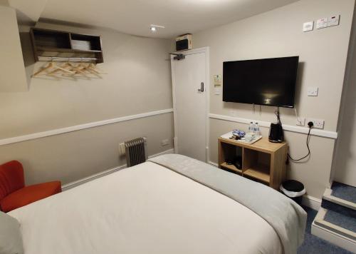 a hotel room with a bed and a flat screen tv at The Swan Hotel in Hythe