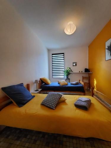 a bedroom with two beds with blue pillows at Chez Jollyjune, à moins d'une heure du Mont Saint Michel in Champeaux