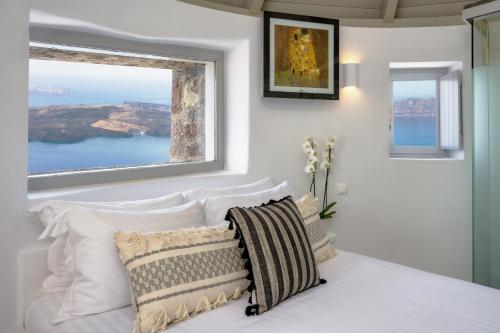 1 dormitorio con cama con almohadas y ventana en Windmill Villa en Imerovigli