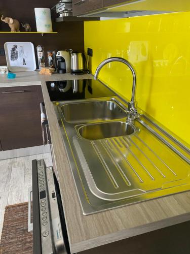 un évier en acier inoxydable dans une cuisine avec un mur jaune dans l'établissement Il Castellaccio, à Tirano