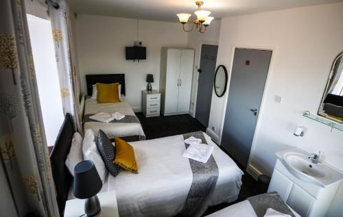 een hotelkamer met 2 bedden en een wastafel bij St Hilda Guesthouse in Liverpool