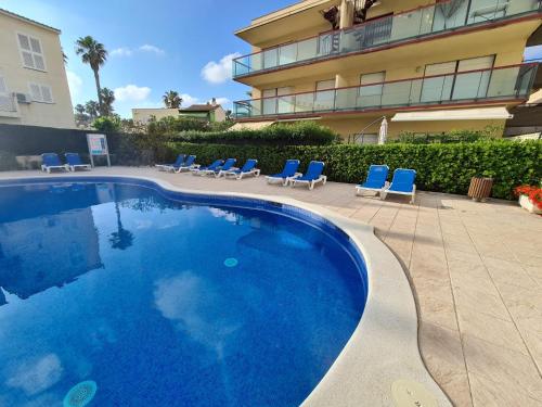 a large swimming pool with blue chairs and a building at Mediterraneo in La Pineda