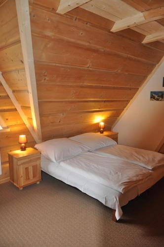 a large bed in a room with wooden ceilings at Gościniec u Groszka in Bukowina Tatrzańska