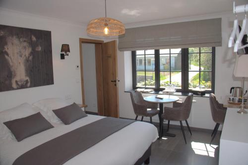 a bedroom with a bed and a table with chairs at Auberge la Hutte Lurette in Paliseul