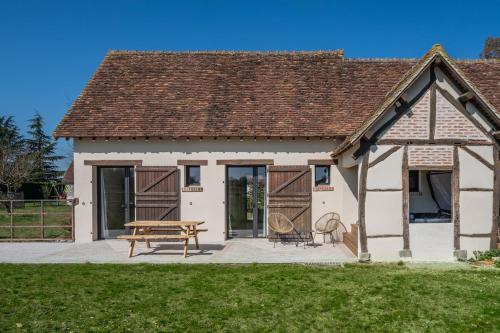 a detached cottage with a picnic table and a picnic bench at La Grange De Léonie, Chambres d'hôtes avec Piscine et Spa in Vierzon