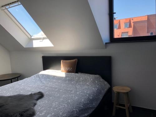 a bedroom with a bed and a window and a stool at BLOC79/4 in Knokke-Heist
