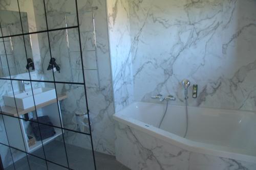 a bathroom with a bath tub and a sink at Auberge la Hutte Lurette in Paliseul