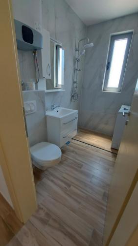een badkamer met een toilet, een wastafel en een raam bij Hotel Kaligrosh in Sutomore