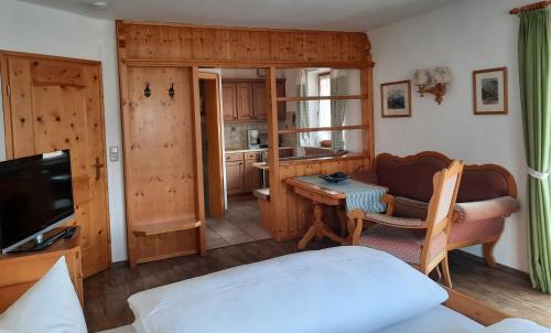 a room with a bed and a table and a television at Gästehaus Annemarie in Reit im Winkl