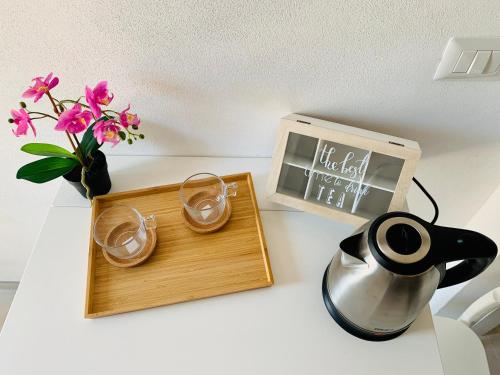 una mesa con una bandeja con dos vasos y un jarrón con flores en La Stanza Dei Desideri, en Peschici