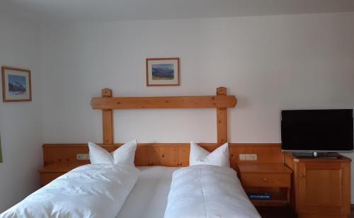a bed with two pillows and a television in a bedroom at Gästehaus Annemarie in Reit im Winkl