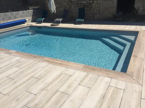 uma piscina com piso de madeira e água azul em Chambre Au clos des auges em Saint-Saturnin-du-Bois