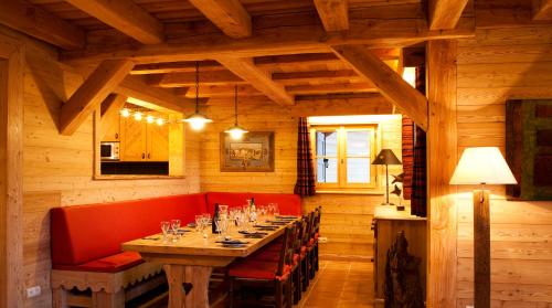 une salle à manger avec une longue table et des chaises rouges dans l'établissement Madame Vacances Chalet Marmotte, à Huez
