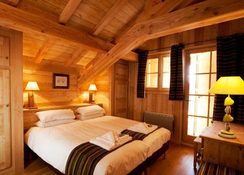 a bedroom with a large bed in a wooden room at Madame Vacances Chalet Marmotte in LʼHuez