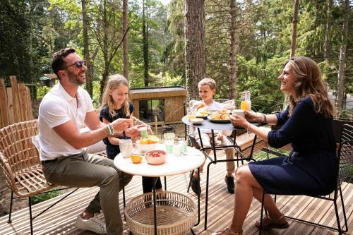 a group of people sitting around a table eating food at Bain de forêt - Lodges Cosy & Spa in Neufchâtel-Hardelot