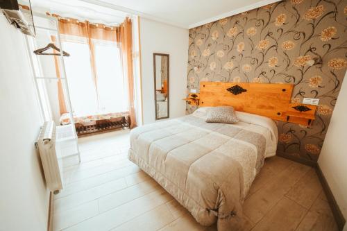 a bedroom with a bed and a wall with floral wallpaper at Hospederia Rincon De Leon in León