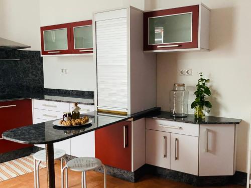 eine Küche mit roten und weißen Schränken und einem Tisch in der Unterkunft Apartamenro A Tixola casco histórico in Pontevedra