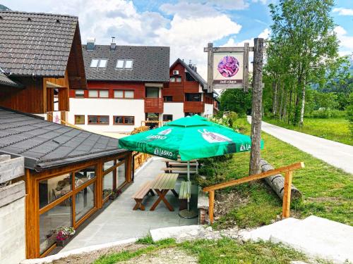 un parasol vert assis devant un bâtiment dans l'établissement Apartment and rooms Maraton, à Kranjska Gora