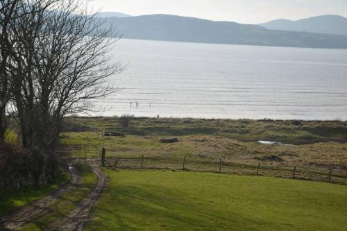 a field with a fence and a view of the water at Cecil's Cottage, Ballynary, Buncrana by Wild Atlantic Wanderer in Buncrana
