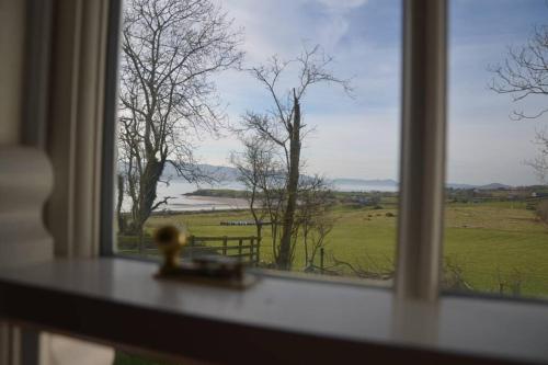 a window with a view of a field and trees at Cecil's Cottage, Ballynary, Buncrana by Wild Atlantic Wanderer in Buncrana