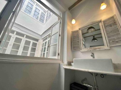 Un baño con lavabo y una gran ventana. en Anticuario en el Teatro Falla, en Cádiz