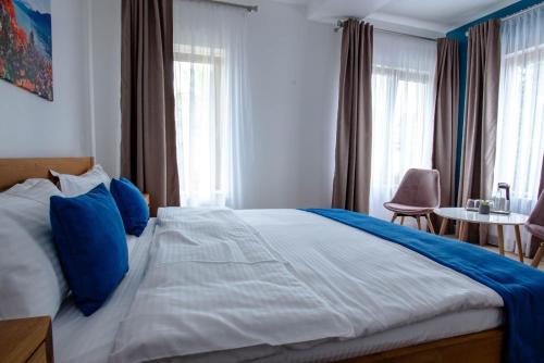 a bedroom with a large bed with blue pillows at English House in Bistriţa