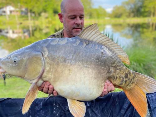 a man holding a large fish in his hands at L’Etang Carp fishing lake and Gite in Saint-Junien