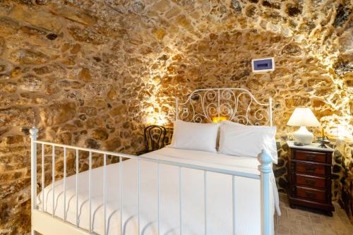 a bedroom with a white bed in a stone wall at Diamante Stone House in Sitia