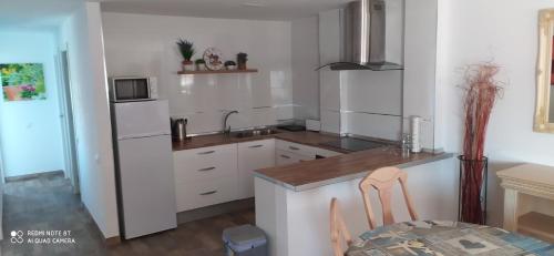 cocina con armarios blancos, fregadero y mesa en Apartamento en Las Marinas Vera, en Los Amarguillos