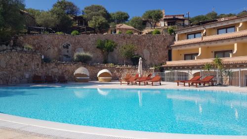 a swimming pool with chairs and a building at Hotel Pozzo Sacro in Olbia