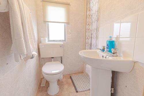 Skye Holiday Chalets C1 في ويج: حمام ابيض مع مرحاض ومغسلة