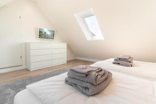 a white bedroom with two beds with towels on them at Ankerplatz in Tönning