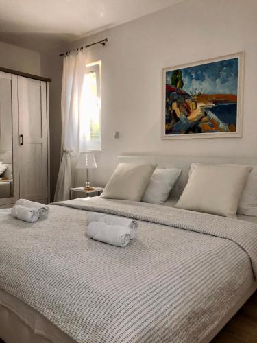 a white bedroom with two beds with towels on them at Villa Dora - Mediterranean family house for 9 with private garden, BBQ, sea view and private parking for 4 cars in Pag