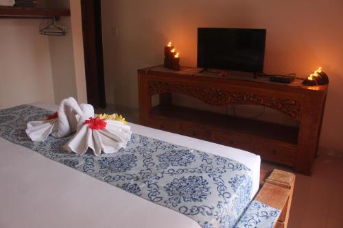 a bedroom with a bed with a television and candles at Jukung Villas Kuta in Kuta