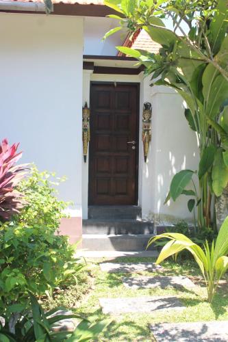 a wooden door on a white house with plants at Jukung Villas Kuta in Kuta