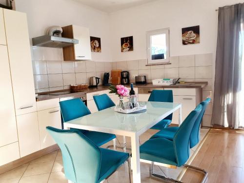 kuchnia ze stołem i niebieskimi krzesłami w obiekcie Apartmani Apolon w mieście Starigrad-Paklenica