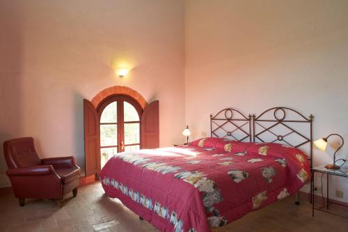 a bedroom with a red bed and a chair at Castello di Modanella in Rapolano Terme
