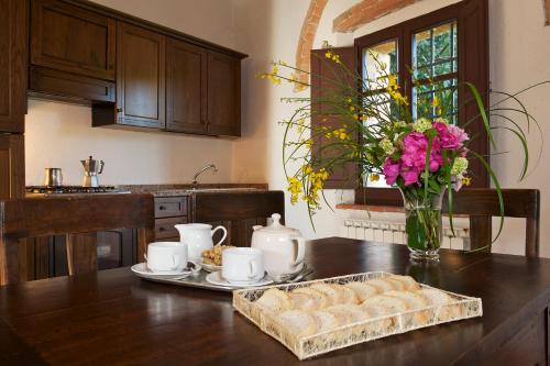 a kitchen table with a tray of bread and a vase of flowers at Castello di Modanella in Rapolano Terme