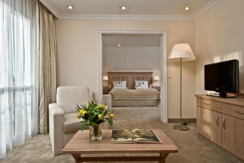 a living room with a couch and a television at Hotel Maximilian in Bad Griesbach