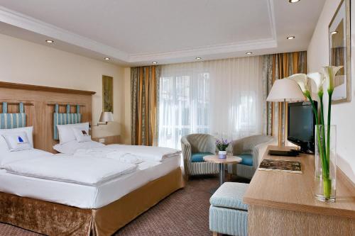 バート・グリースバッハにあるHotel Maximilianのベッド2台とテレビが備わるホテルルームです。